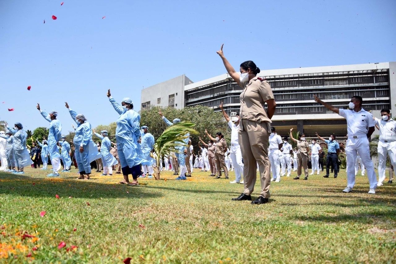 Health workers cheer and wave at Indian Navy's Chetak helicopter as it showers flower petals on INHS Asvini Military Hospital in Mumbai to show honour and express their gratitude towards the coronavirus warriors who are battling the pandemic, during the extended nationwide lockdown imposed to mitigate the spread of COVID-19, on May 3, 2020. (Photo: IANS)