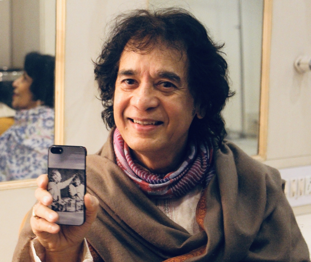 Zakir Hussain holds up his phone cover, which has a picture of him and his father playing tabla