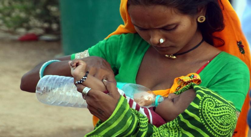 New Delhi: A mother feeds water to her child on a hot day in New Delhi, on May 17, 2016. (Photo: IANS)