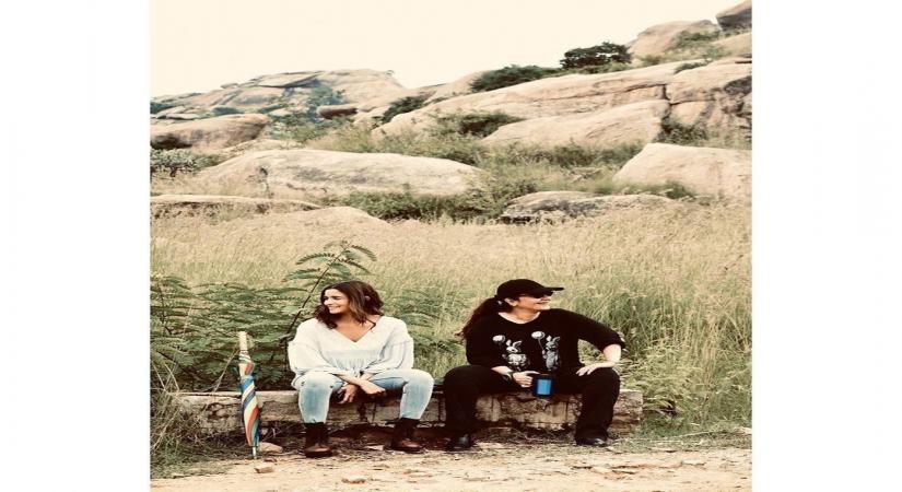 Actress Alia Bhatt has shared some "priceless moments" with her "big sister" Pooja sister from the sets of "Sadak 2". Alia on Friday took to Instagram and Twitter, where she shared a photograph of herself along with Pooja sitting on a log. Alia is seen in a white tunic paired with light blue denims, while Pooja is sporting an all-black look.