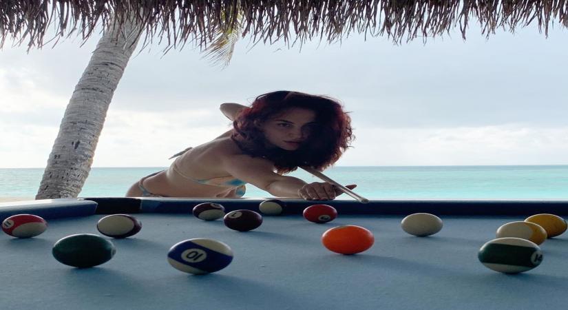 Elli AvrRam plays pool in bikini by the beach.