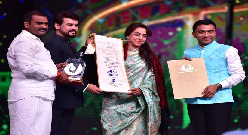 Panaji :Actress and MP Hema Malini receive Indian Film Personality of the Year 2021 Award from Union Minister of Information and Broadcasting,Youth affairs and sports Anurag Thakur with Goa CM Pramod Sawant during the opening ceremony of 52nd International Film Festival of India in Panaji,Goa on Saturday November 20,2021.(Photo:PIB/IANS)