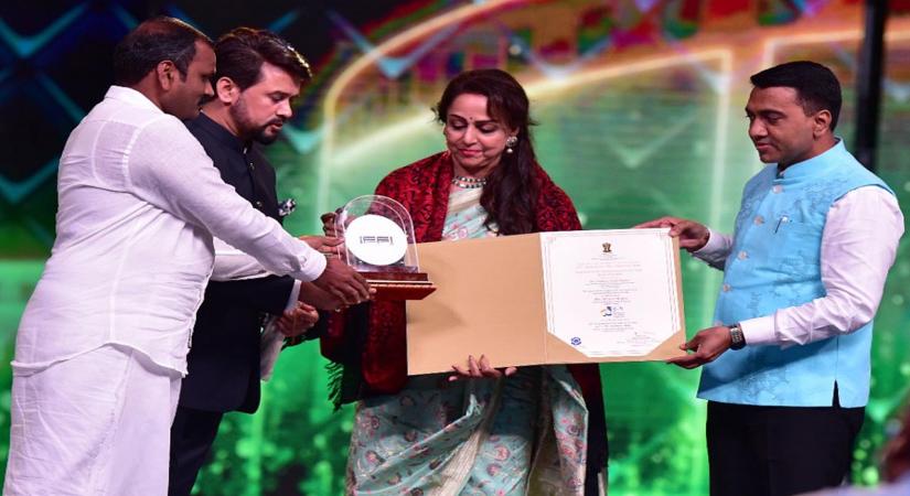Panaji :Actress and MP Hema Malini receive Indian Film Personality of the Year 2021 Award from Union Minister of Information and Broadcasting,Youth affairs and sports Anurag Thakur with Goa CM Pramod Sawant during the opening ceremony of 52nd International Film Festival of India in Panaji,Goa on Saturday November 20,2021.(Photo:PIB/IANS)