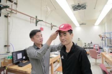 University of Wisconsin-Madison Materials Science and Engineering Professor Xudong Wang (left) and colleagues developed a device -- unobtrusive enough to fit under a cap -- that harnesses energy from the wearer and delivers gentle electric pulses to stimulate dormant hair follicles and regrow hair. (Photo: UW-Madison by Sam Million-Weaver)