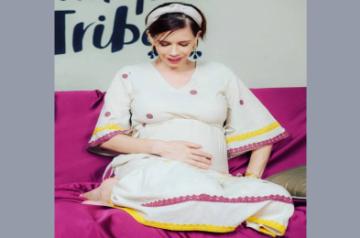 Actress Kalki Koechlin has shared her first pregnancy photograph flaunting her blossoming baby bump on social media. Kalki on Monday took to Instagram to share the image. In the photograph, the "Dev. D" actress is seen sitting on a couch in a beautiful white cotton dress.